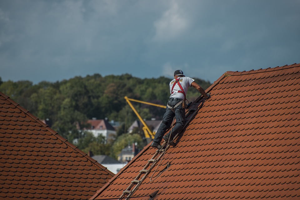 A person adding shingles to a roof.